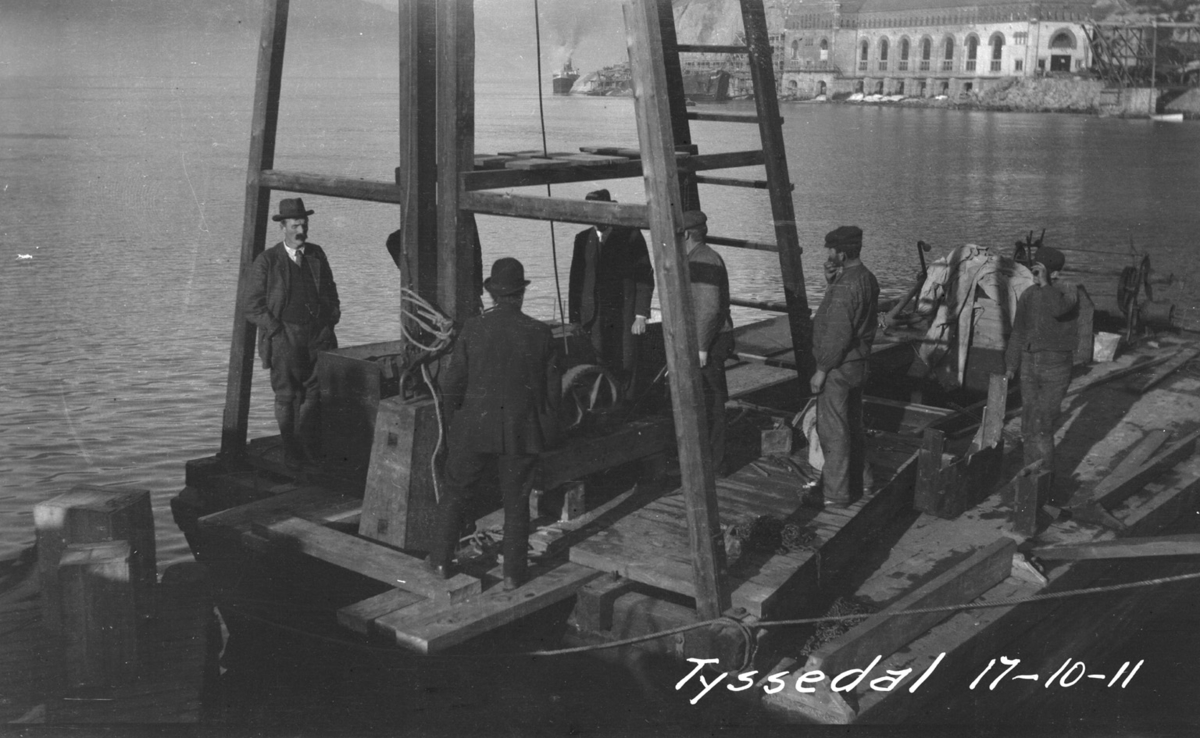 Funksjonærar og arbeidarar på ein flåte med vannbokk på kaia i Tyssedal i 1911.