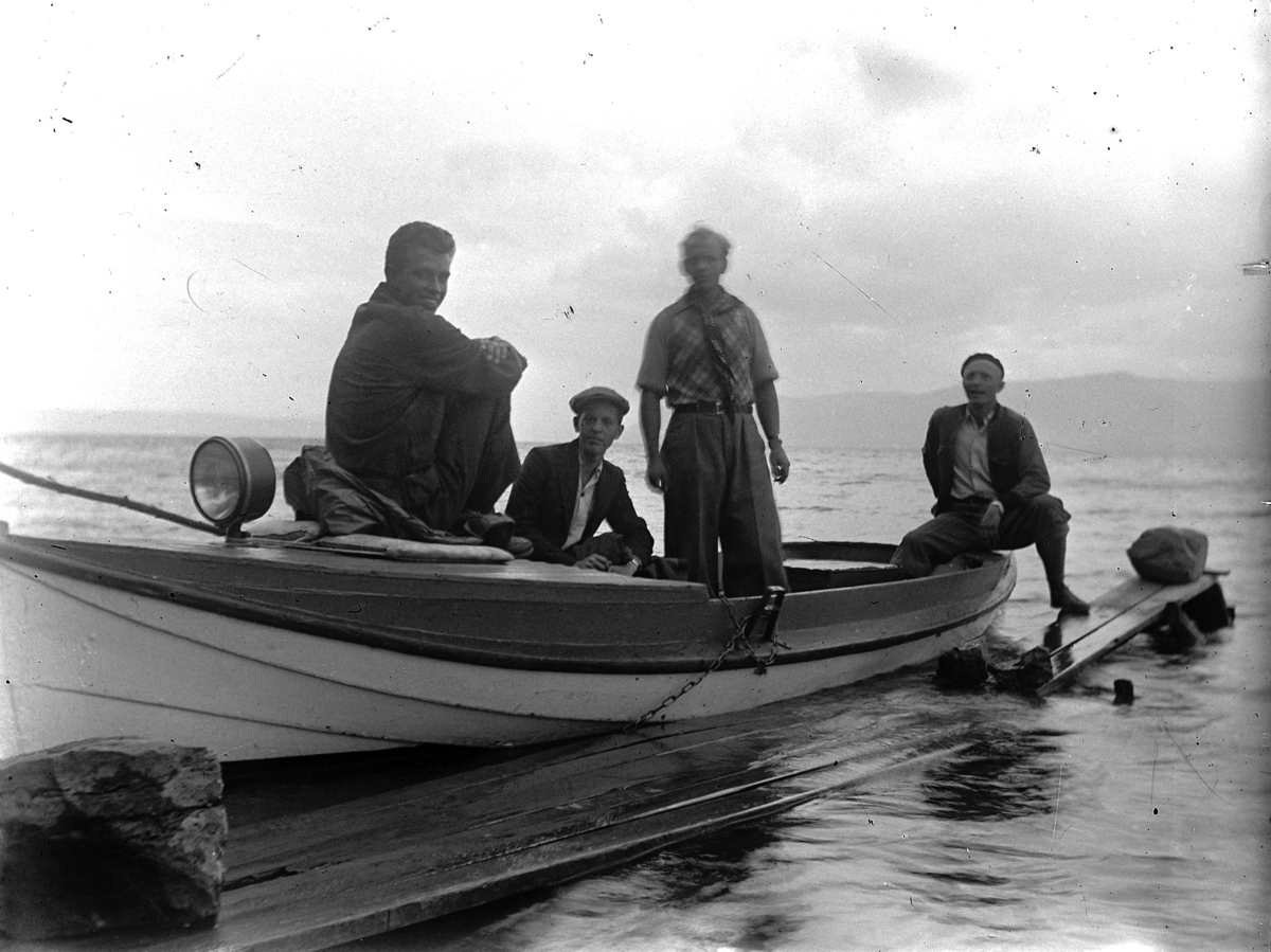 Gruppe, fire mann i båt, ved brygge. nedenfor Kvalstua, Helgøya.