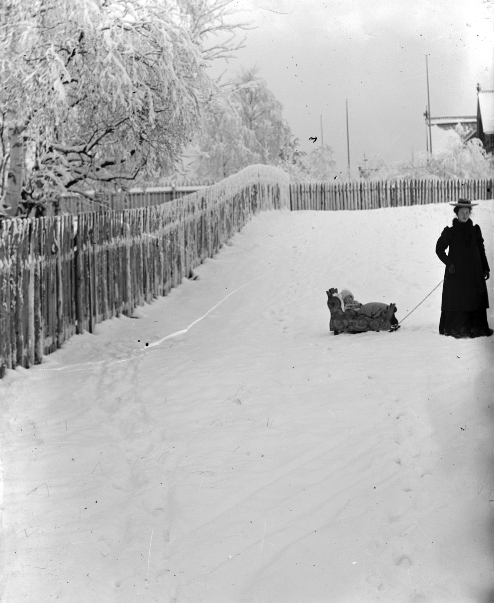 Hamar,  St. Olavs gate 66, Johanne Alhaug (1886-1979) med sin datter på en kjelke utenfor Holmsgården: enten Eva Alhaug (1909-) eller Margit Alhaug (1904-)