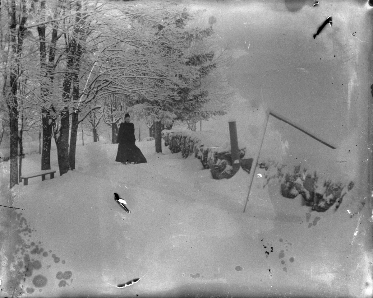 Ringsaker, Nes, Grefsheim gård, Vinter. Ukjent kvinne ved et steingjerde langs en vei. 