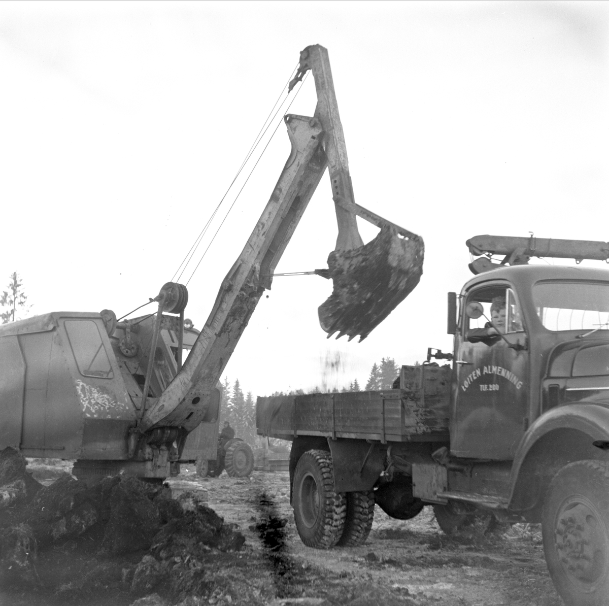 SENTRALIDRETTSPLASSEN I LØTEN, GRAVEMASKIN OG LASTEBIL FRA LØITEN ALMENNING KJØRER VEKK MASSE, 1958/59. SE BOKA PÅ ET HUNDREDELS SEKUND, LØTEN OG OMEGN 1957-1964 I ORD OG BILDERAV HELGE REISTAD S. 56. 