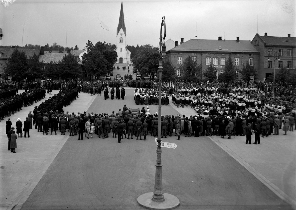 NASJONAL SAMLINGS JONSOKKSTEVNE PÅ HAMAR I 1942. OPPSTILLING PÅ STORTORGET. OPPSTILLINGA VAR NØYE REGISSERT MED TALER OG NS-PROMINENSER I KIRKEBAKKEN. KVINNE OG JENTEAVDELINGENE T. H, FØRERGARDEN, RIKSHIRDEN, HIRDEN OG UNGDOMSFYLKINGEN T. V. FOTO NORMANN, HAMAR. 