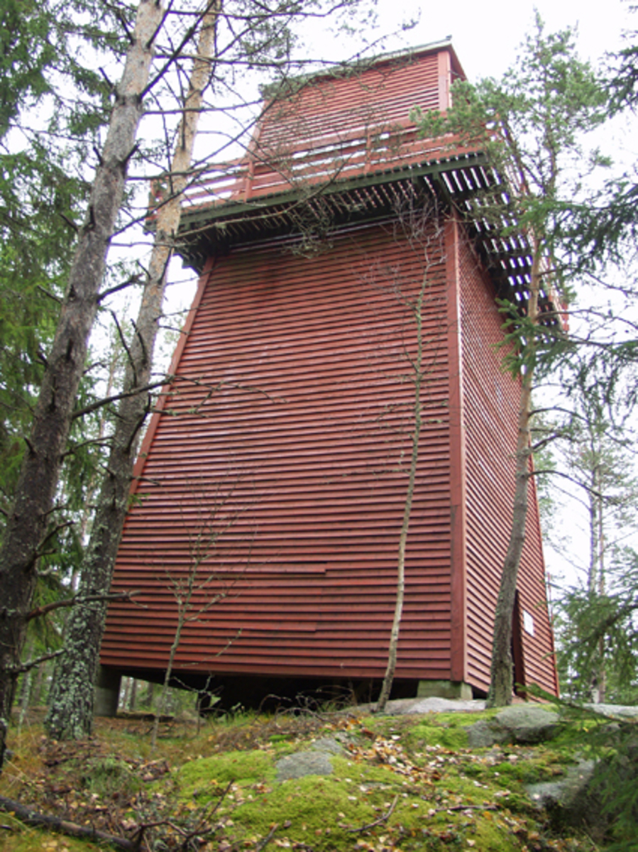 Skogbrannvakttårnet på Hauknesfjellet i Rømskog i Østfold.  Fotografiet ble tatt i forbindelse med oppmålingsarbeid da Norsk Skogmuseum begynte å arbeide med planer om å bygge en kopi av tårnet på museumsområdet i Elverum. 

Tårnet på Hauknesfjellet ligger 335 meter over havet med fin utsikt over vide skogtrakter.  Det første tårnet på dette stedet ble reist i 1909, det neste i 1928.  Det avbildete tårnet skal etter informasjon i forsikringsselskapet Skogbrands arkiver å dømme være bygd i 1953.  Det er reist på et skjellett av stolper (rundtømmer) som er kledd med rødmalt horisontal bordkledning (vestlandspanel).  I den øvre delen av tårnet er det innredet to rom - et oppholdsrom med utvendig balkong på fire sider og et overliggende utkikksrom under en takhatt med vinduer i alle himmelretninger.  Dette fotografiet viser tårnets fasade mot vest. 