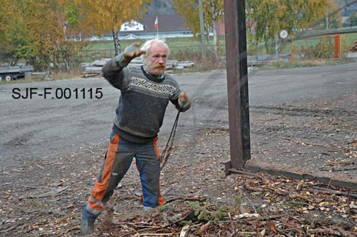 Fra Skiensvassdragets fellesfløtningsforenings utislagsplass på Nesøya ved Notodden.  Fotografiet viser en av medarbeiderne i Skiensvassdragets fellesfløtningsforening, Tom Kaafjeld, idet han kaster et "bilbind" inn i ei såkalt "måleramme" på utislagsplassen. 

Måleramma består av ei rekatangulær betongsåle med tverrgående stålskinner og vertikale stolper i samme materiale i hvert av de fire hjørnene.  Slike rammer var plasseringssted for tømmer som skulle lagres og buntes før det ble slått på vannet.  Oftest ble bunting og utislag gjort direkte fra lastebilene som leverte virket, men når leveransene kom på tidspunkt da terminalplassen var ubemannet, kunne sjåførene legge igjen virket disse rammene. Et "bilbind" besto av cirka ti meter vaier og cirka to meter med kjetting.  I enden av kjettingen var det et pæreformet lås.  Som en sikkerhetsforanstaltning ble låsene surret med tynn stålståd, såkalt blomstertråd.  Bilbindet skulle følge tømmeret fra utislaget til det var fløtet fram til papirfabrikken. 