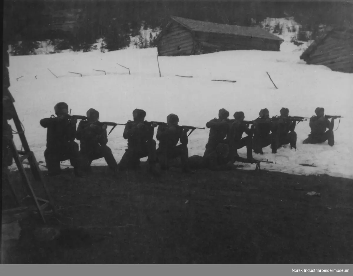 Skyteøvelser for soldatene fra cella i Skirvedalen i Tinn Austbygd. Tørrtrening med US-carabin på vollen ved seteren Fjellie april 1945. Karene på bildet er sannsynligvis fra venstre: Øyvind Norby, Jan Grasdalen, ukjent, ukjent, Knut Klonteig, Olav Kløften, ukjent, ukjent, ukjent og Lasse Jacobsen.