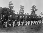 Exercis i pluton på övningsfält på livgrenadjärregementet på Malmen. Soldater i uppställning i två rader. Bakre raden i givaktställning, främre på knä med gevär beredda.