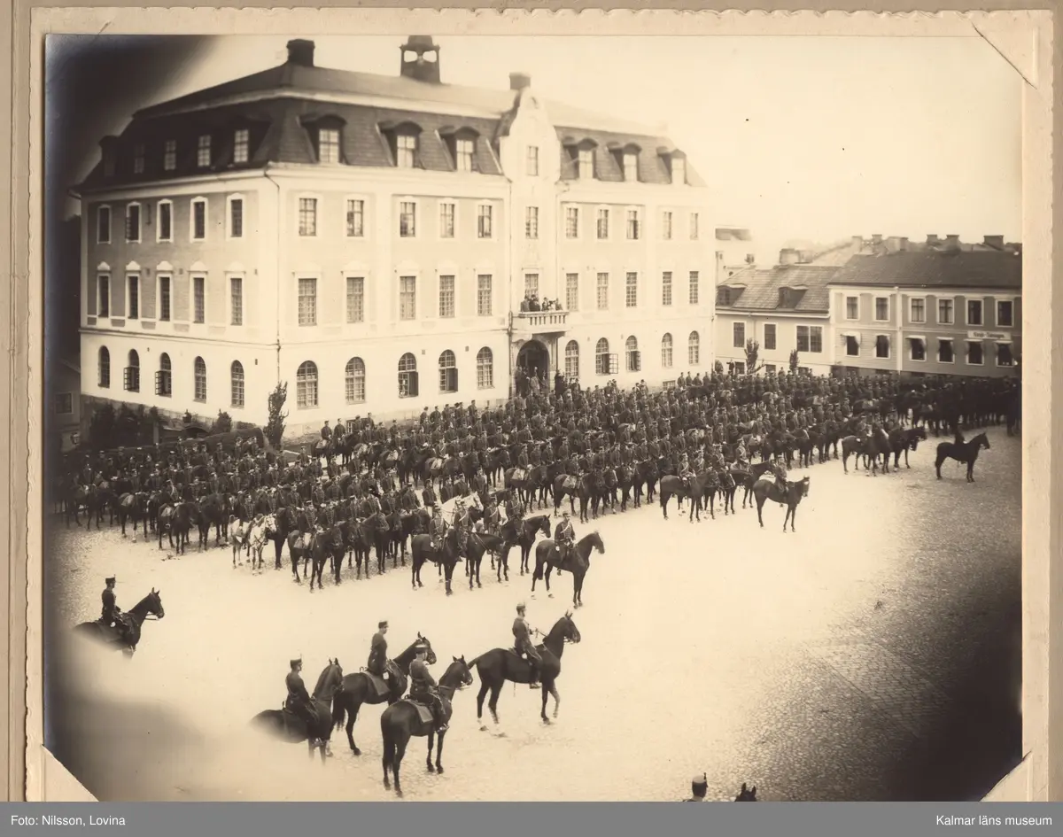 KLM 15433. Fotografi, i grått omslag av kartong. Mått: H 24,5 cm, Br 31 cm. Tre olika fotografier föreställande Kungliga Smålands Husarregementes paradering och gudstjänst på Eksjö torg 1923.