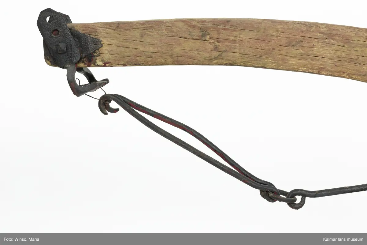 KLM 12824. Plog, trä, metall. Plog med handtag och ås av trä. Landsida av trä, järnskodd. Vändskiva och bill av järn. Tvärslå av järn mellan handtag och ås. Slåar mellan handtagen, två rundformade av järn, en U-formad av järn, en kantig av järn och en av trä. Längst fram på åsen en dragkrok av järn med reglage för inställning av höjd. På åsens mitt en fastskruvad rist. Risten är sammanfogad, eventuellt med färg, med billen. Tre långa krokar av järn hänger under åsen och möts i en järnring. Plogen är trasig på landsidan, träet är sprucket och järnbeslaget har lossnat. Plogen är rödmålad men färgen är kraftigt avskavd. Plogens järndetaljer är svartmålade med en röd eventuell rostskyddsfärg under. Den svarta färgen och rostskyddsfärgen är målad senare.