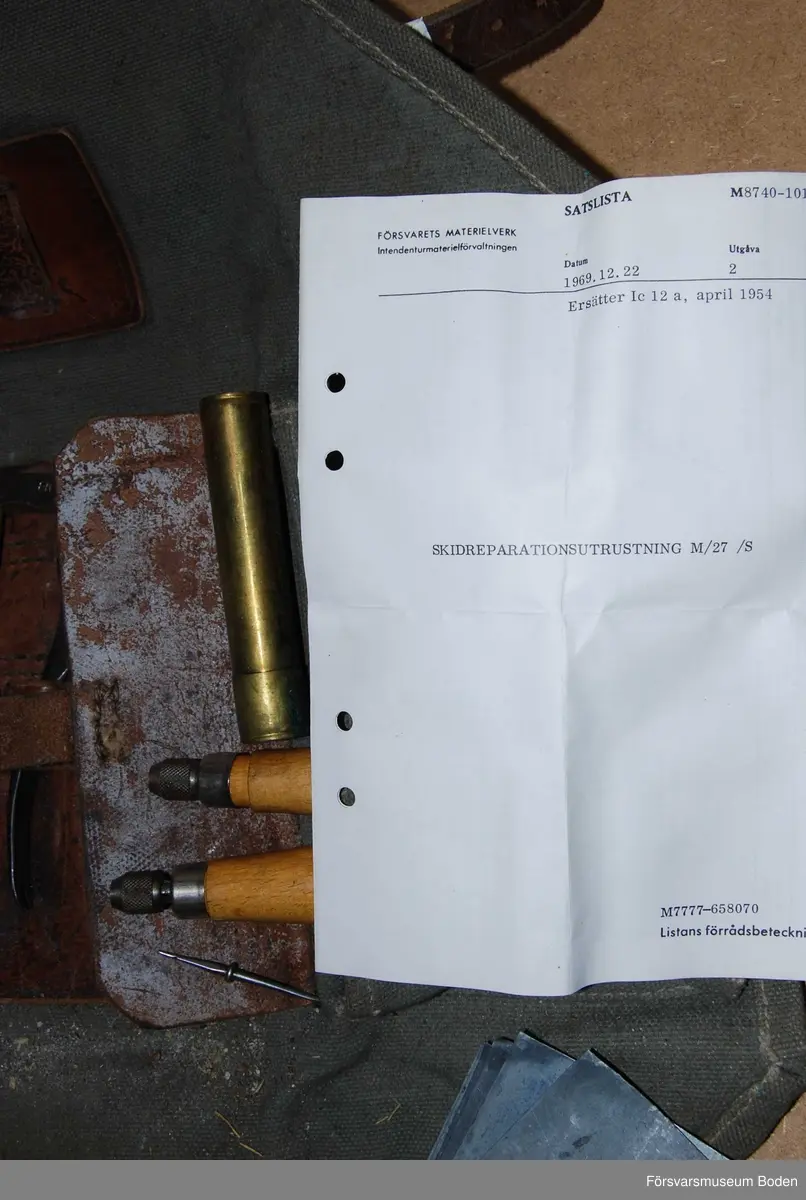 Verktygssats i väska av grågrönt textilmaterial med axelrem. Innehåller även förbrukningsmateriel som bleckplåtar, wire, nitar o.dyl. Väskan vikes upp och har hållare för verktyg i centrum samt tre fickor med lock. Materielnummer M8740-101110 enligt bifogad satslista.