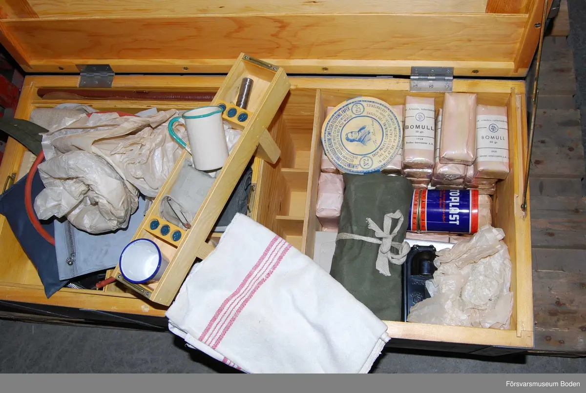 Låda av grålackerat trä med järnförstärningar innehållande sjukvårdsutrustning för häst. Locket försett med hänglås och två nycklar. På gavlarna finns lyfthandtag och hästsymbol målad med schablon. Satsnummerr V23, materielnummer M8288-121000.