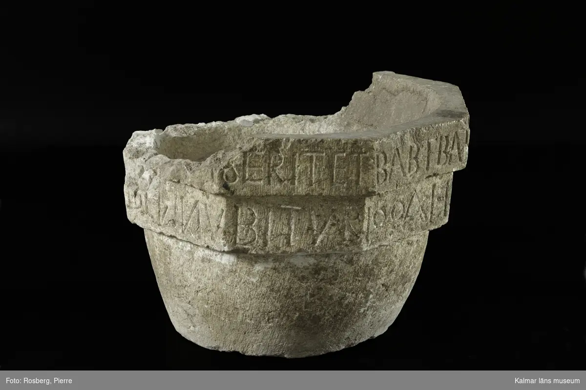 KLM 35218:1:1-4. Dopfunt, av kalksten, består av 4 delar. :1:1. Dopfuntscuppa, mått: mynning yttre diameter 65 cm, inner diameter 50 cm, skåldjup 18 cm, botten diameter 40 cm. Cuppan utförd i tre nivåer, de två övre delarna är åttakantiga och underdelen cylindrisk med svag konisk-konvex profil. Den övre åttakantiga nivån med latinsk inskription, text med versaler, inskrift: ...ERIT ET BABTATUS FUERIT SALV... Den undre åttakantiga nivån har texten ...RIT CONDEMNABITUR. (Inskriften är ej helt komplett, del av citat från, Marcus 16:16. Hela citatets översättning, Bibeln 2000: Den som tror och blir döpt skall räddas, men den som inte tror skall bli dömd.)  Den undre nivån har kryssristad dekor. Underdelen är odekorerad. Grund skål. Cuppans överkant, är till hälften bortslagen, tre av bitarna finns kvar. Utan uttömningshål. :1:2-4 tre lösa delar tillhörande övre kanten av cuppan. Alla tre delar har otydlig latinsk inskription, text med versaler och tecken.