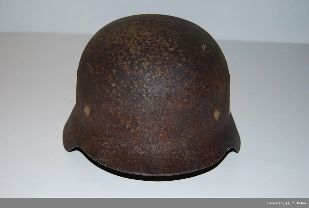 Kanten omvikt mot insidan. Inredning med aluminiumband, stämplat 1938. Rester av grön färg på insidan. Dekaler på båda sidor, varav endast rostkonturerna syns på den vänstra sidan. Storlek 59