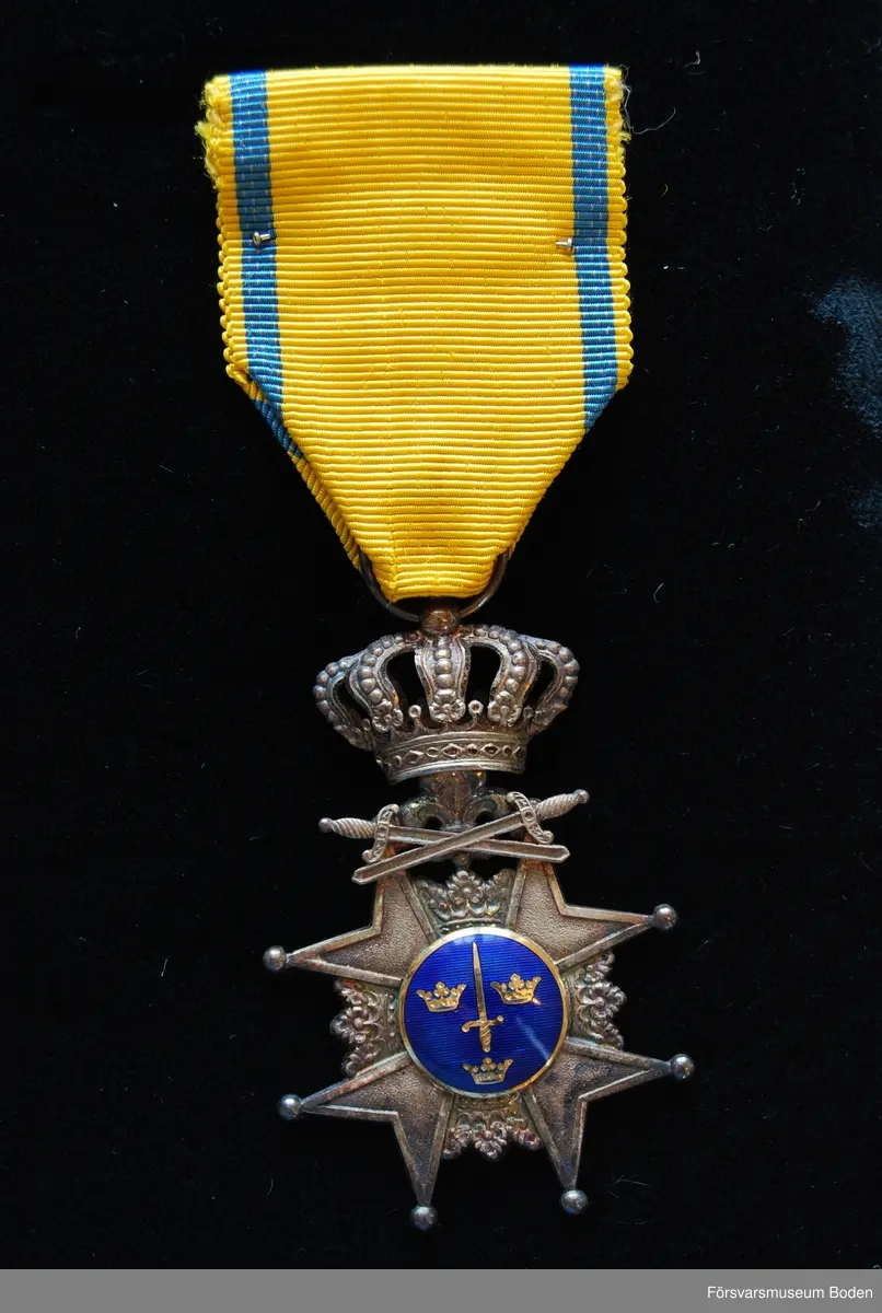 Tavla med uppsatta medaljer på svart sammet. Har tillhört Karl Hjalmar Lindskog, finlandsfrivillig 1939-1940. Från vänster på bilden:
1. Vinterkrigets minnesmedalj med svärd och spänne, Lappi, järn. Urkund finns i pärm under FMB.002361.
2. Frihetsmedaljen 2.klass, brons, urkund finns i pärm under FMB.002361.
3. Medalj från Föreningen för skolungdomens vapenövningar, silver.
4. Svärdstecken.
Överst på tavlan ett släpspänne för dessa medaljer.
