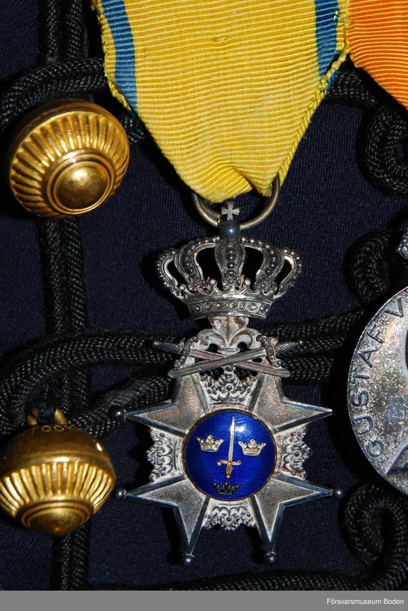 Silver med blå emalj i centrum på framsidan. Ingen emaljering på baksidan, som har texten Pro Patria och ett svärd med lagerkrans.  För underofficerare efter 16 års tjänst.