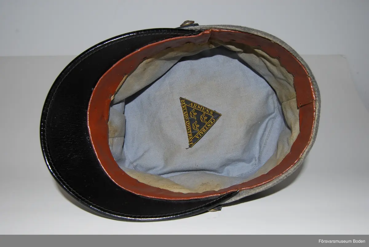 Ljusgrått kläde med tre smala band av blått kläde runt mössan betecknande kapten. Framtill mössmärke m/1865 i blå emalj samt upptill landstormsmärke m/1926 med gult broderat kors på blått kläde. Mössremmen fäst på sidorna med landstormens knapp modell mindre. Buren av fil. dr Arvid Moberg.