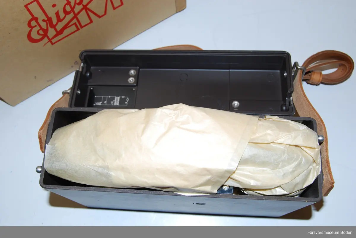 Ny i öppnad kartong. Telefonapparat m/1937 utan LB/CB-omkopplare och klyka. Tillverkad under vecka 50 1963 enligt stämplar på chassi och emballage. Inget synligt serienummer i övrigt.