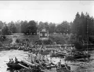 Ing 2, broslagning av krigsbro vid Gullspång 1910. Sergeant Forsberg och sergeant Aronsson..Objektkommentar:Fråga synes vara om byggation av, från höger, dels en färdog spång, dels pågående byggnation av en s.k. fältbro(S.k. nödfallsbrygga). Till vänster syns en pålkran för islående av pålartill fältbrons stödelement.Bilden kan vara tagen i trakten av Gullspång, där Göta Ingenjörbataljon hade en sommarövningsplats 1893-1911.Bilden kan vara tagen under marschernamellan Karlsborg och Gullspång, eller i biflödet av Gullspångsälven nedanför fallet, där läger och övningsplatsen fanns. Se vidare tidskrift i Fortifikation årgång 2002 nr 2, s.38 ff.