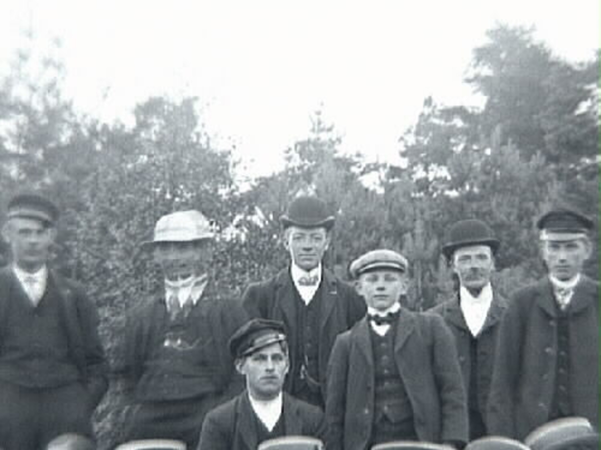 Gruppbild med c:a tjugo personer fotograferade utomhus. Mannen med plommonstop, stående trea fr vänster är Klas Johansson i Stenshult, född 1888.