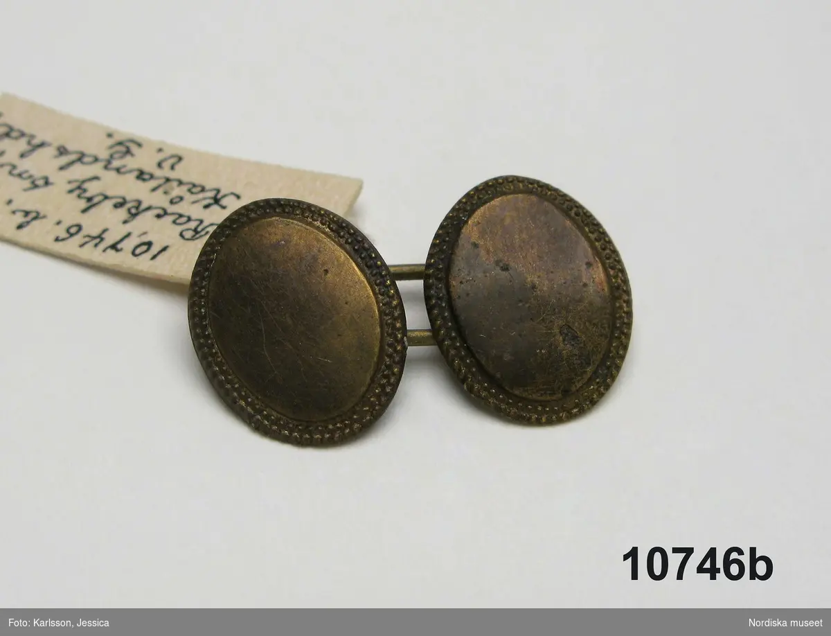 a. Kvinnokrage i form av ett rynkat krås, av halvlinnelärft med rosa korssömsbroderi, märkt MAD 1847
b. Tillhörande länkknapp av mässing.
/Berit Eldvik 2010-09-21