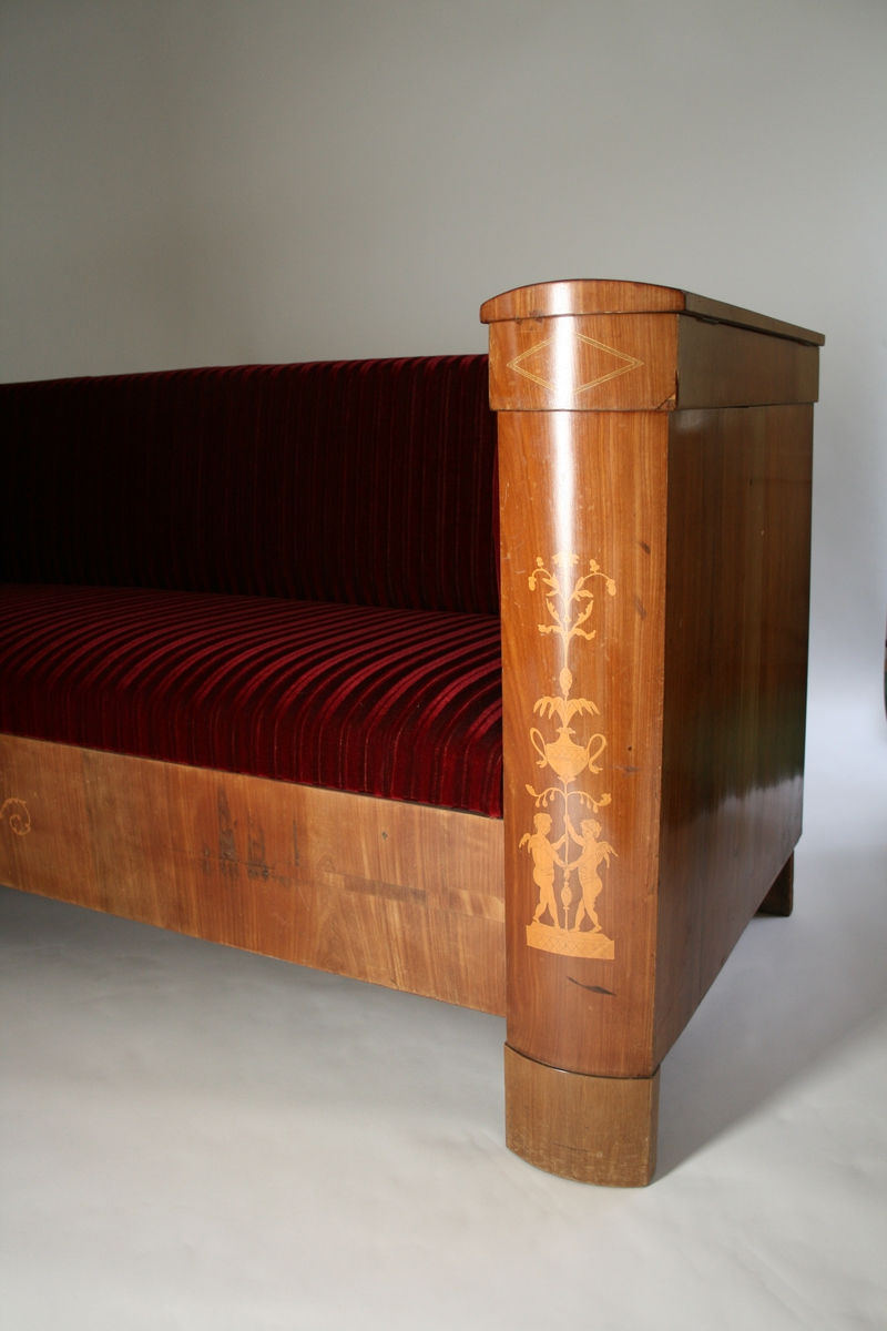 Med leddiker, intarsia - kjeruber med urner.  To lokk på rom i venstre leddik.
Trukket i dyp rød velur. Trekket er ikke opprinnelig