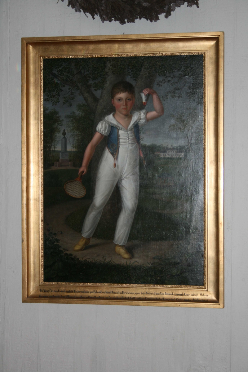 Barneportrett, helfigur. Gutt i hvit drakt med blå vest, empiredrakt. Han holder en racket i høyre hånd, og en fjærball i den venstre.