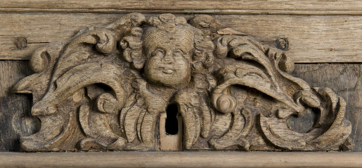 Rektangulært skap med skåret ornamentikk i flere deler. Øvre skap med to dører og gesims. Nedre skap med en klaff fremstilt som to dører. Skapdelene står på en sokkel med fire ben. Tympanon på øvre skap. Skapet ble opprinnelig brukt som skjenk med åpen klaff for å servere drikkevarer til gjester.
På overskapet i dørfyllinger er utskåret motiv fra gamle testament: "Samsons kamp med løven" og "Samson bærer bort Gazas byport". På underskap i fyllinger: "Samson slår filisterne med asenkjeven" og "Samson og Dalila". Dørene blir flankert av hermenpilaster. Mellom fyllinger på overskap aedikula med dyden "kjærlighet".  Som karyatide og atlant to utskårete figuerer "Adam og Eva" ved overskap. 
Klassiske profiler med eggstav, perlestav og tannsnitt. Beslagverkornament på skapsidene, gesimsens underside og profil på underskap. 
Utskårete hoder av løver, engler, kvinner, masker på gesimsens underside og profil på underskap. Sidebrett med hermer, portretter i medaljonger og beslagverk. Sokkelen består av dreide og utskårete ben, holdt av en ramme, Forsidens blending er dekorert med utskårete figurer og ornamenter i ørebruskstil.
Flere deler er sekundære.