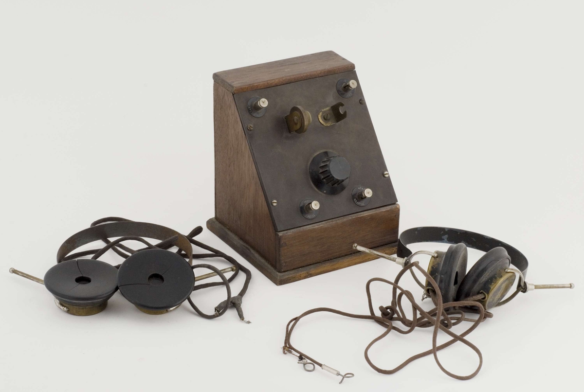 Krystallapparat med to sett høretelefoner. Fire "knapper" merket "antenne", "jord", "telefon", "telefon". 