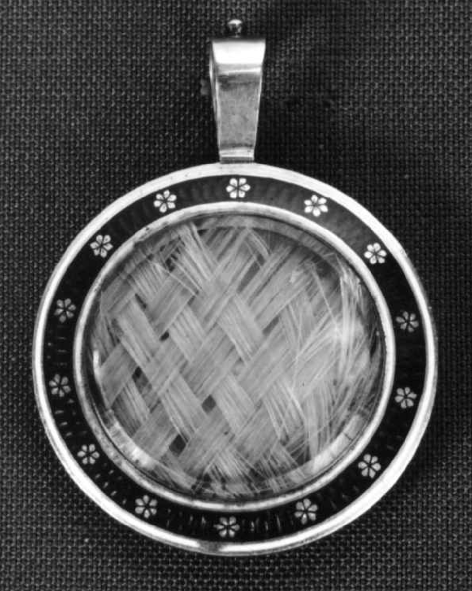 Medaljong med flettet hår og tørkede blomster inni.