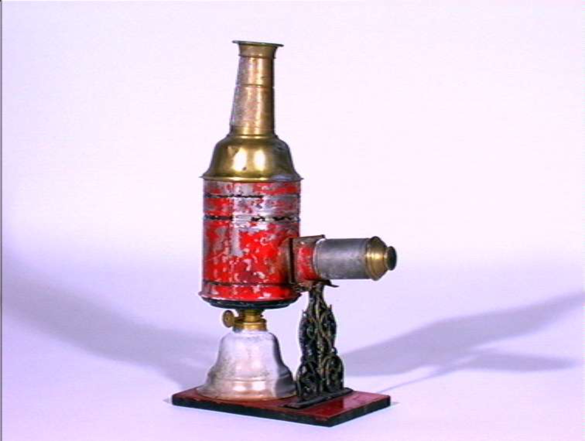 Lysbildefremviser i flere deler med parafinlampe. 12 glassplater med forskjelliger motiver i lysebrune rammer hører til.