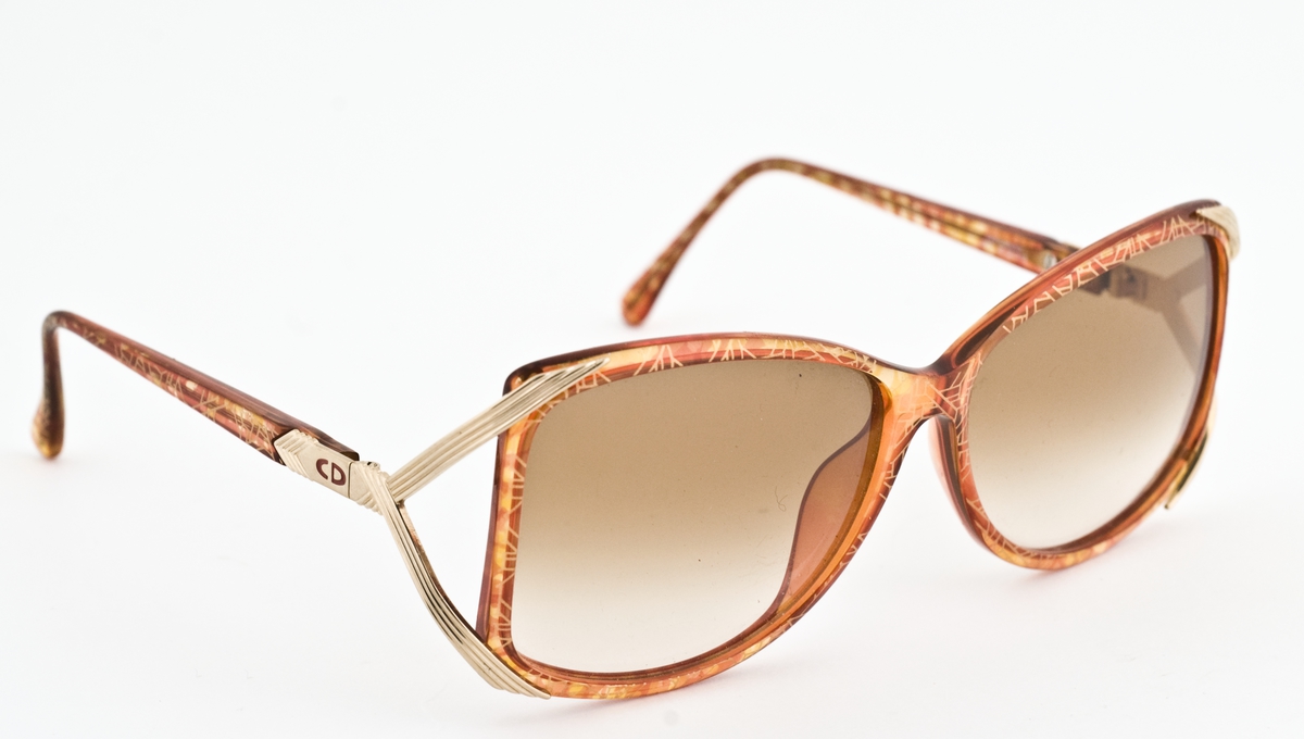Rød- og gullfargemønstret solbrille av plast.