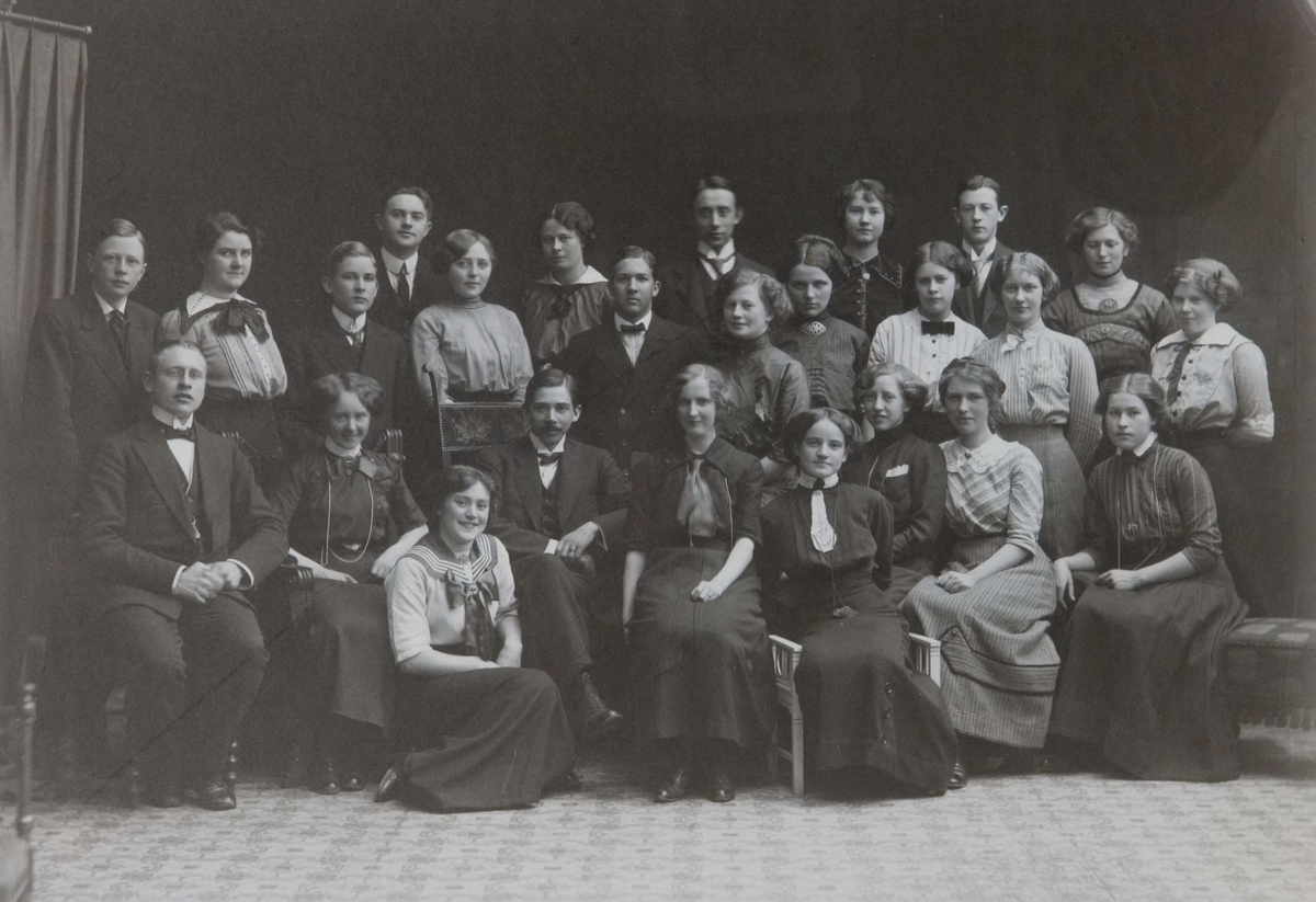 Gruppefoto av studenter til farmasøytisk medhjelpereksamen, syv unge menn og seksten unge damer. I midten Hans Marius Moa som ledet kurset.