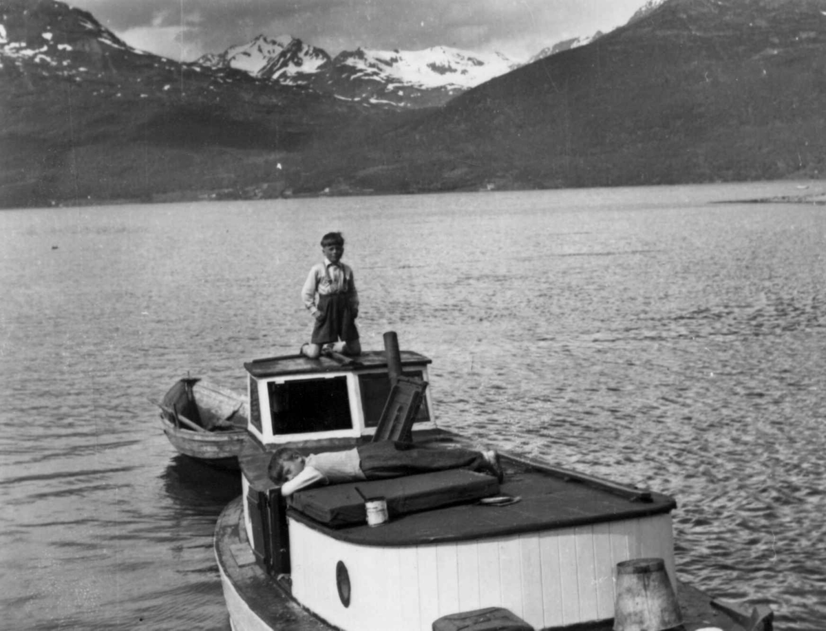 Kjøpmann Harald Heims motorbåt med to barn på dekk på Ullsfjorden, Stordalen i bakgrunnen, 1952.