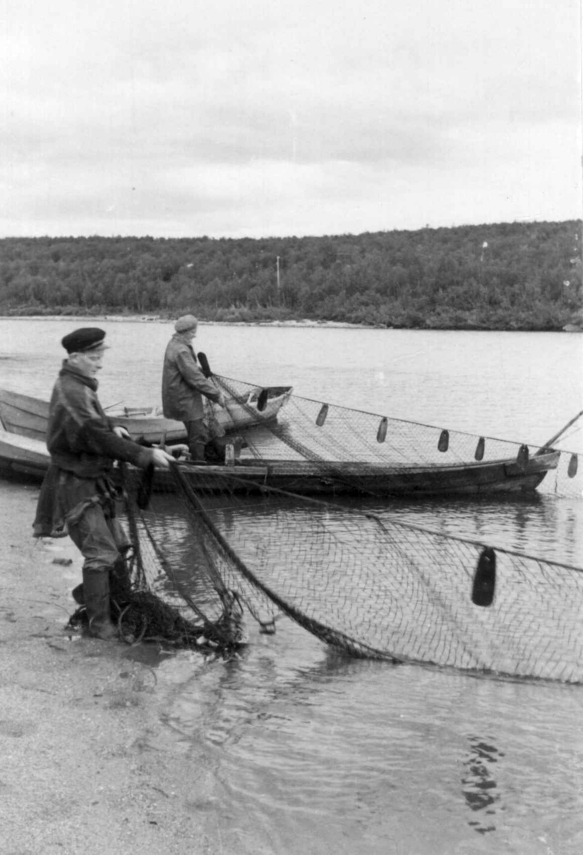 To personer, en på land og en i båt, haler inn notgarnet. Kautokeino 1953.