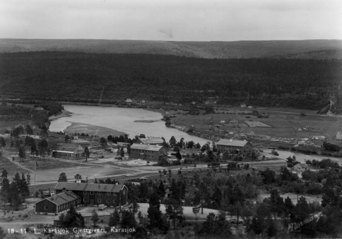 Oversiktbilde over Karasjok kirkested, Finnmark, med Karasjok gjestgiveri i forgrunnen. Bildet må være tatt før 1952 siden barneskolen ikke er på bildet, den ble tatt i bruk 1953. Hotellet og den samiske folkehøgskolen er med. Fra prospektkort.

