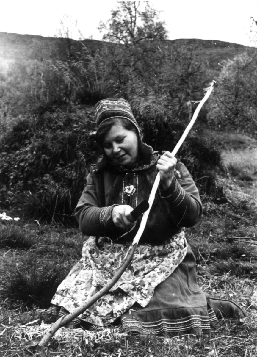 En kvinne skaver vidjebark med kniv til skinnbearbeiding. Masi 1967.