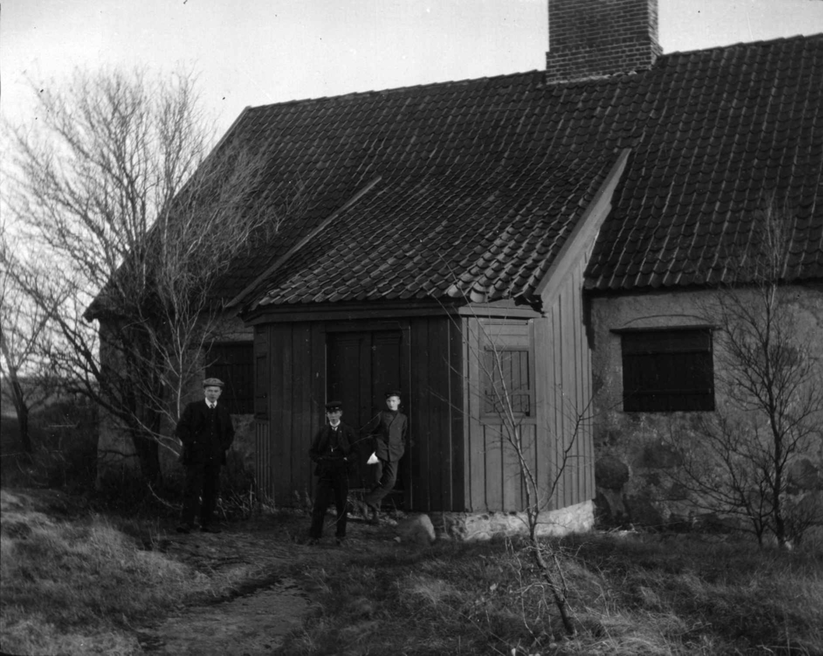 Postkort. Kommandantboligen på Kongssted, Fredrikstad festning. Tre menn foran boligen.