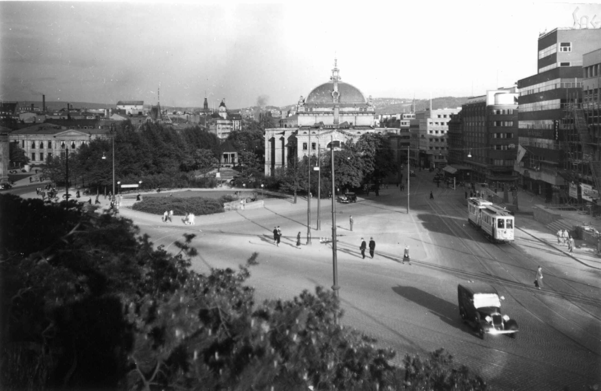 Stortingsgata, Oslo 1936. Oversiktsbilde. Utsikt fra Slottsparken mot Nationaltheatret og nedover Stortingsgata. Universitetet til venstre i bildet. Biler, trikker og fotgjengere.