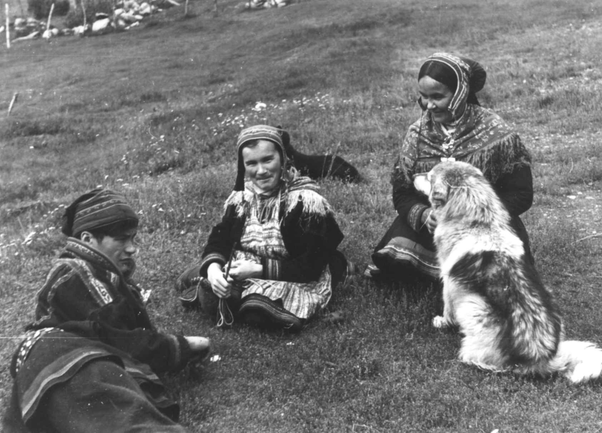 Samer sitter i gresset sammen med en hund. Olderdalen, Kåfjord, Troms 1947.