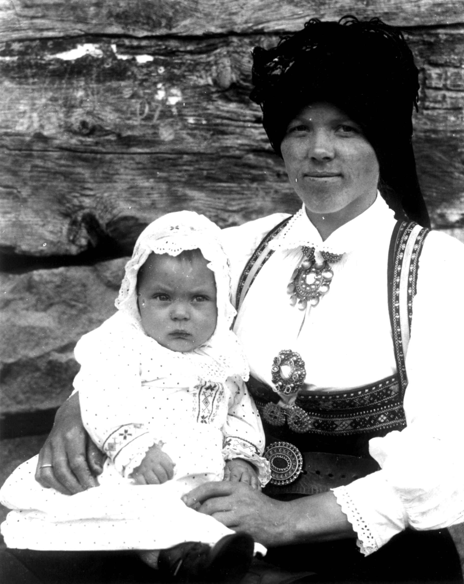 Kvinne- og barnedrakt, gruppeportrett, Valle, Setesdal, Aust-Agder, antatt 1924. Kvinne med spedbarn på fanget. Fra "De Schreinerske samlinger" (skal oppgis).