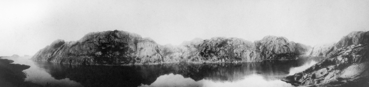 Fjordparti med fjell i bakgrunnen, Jøssingfjorden, Sokndal, Rogaland. Panorama, muligens noe retusjert, deler se NF.15291-025 og -026.