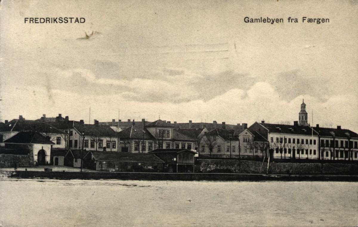 Postkort. Jule- og nyttårshilsen. Motiv fra Fredriksstad: Gamlebyen sett fra ferjen. Murbebyggelse. Stemplet 23.12.1906.