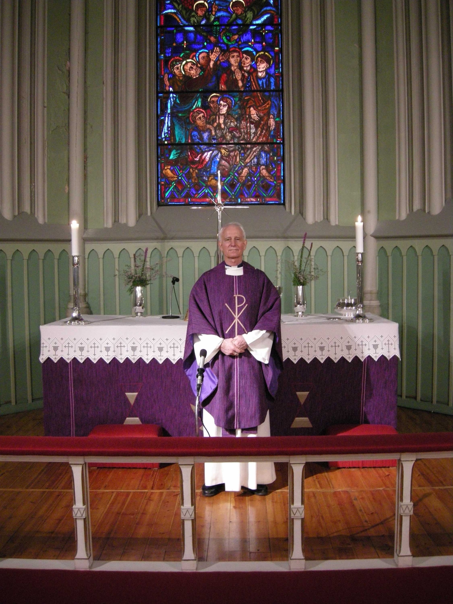 Første søndag i advent, åpning av kirkeåret. Sarpsborg kirke, Østfold, 02.12.2007. Prest kledd i lilla messehagel foran alteret i kirken. Glassmaleri.