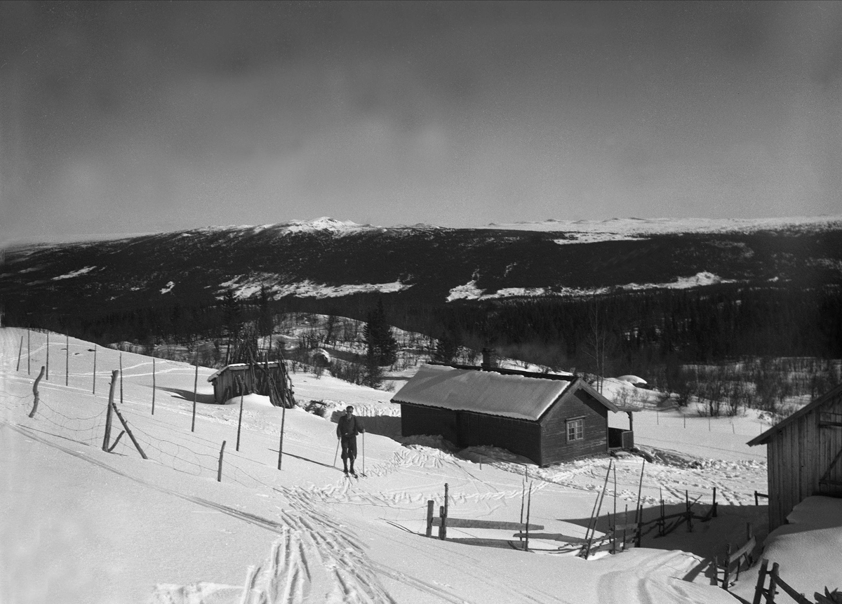 Mann på ski ved en hytte med uthus i Gol, Hallingdal.