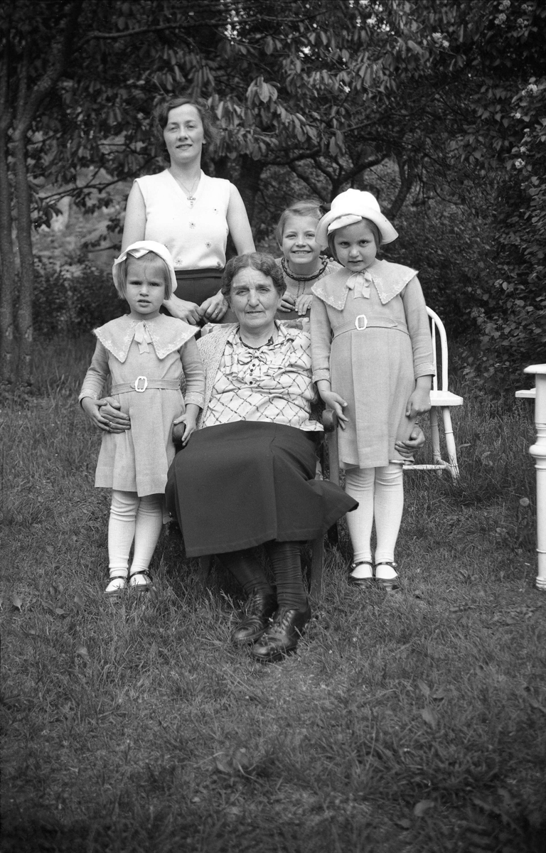 Farmor Dikka Aall Ottosen sammen med barnebarna Siri og Guri Arentz sammen med en venninne og hushjelp på i en hage på Nøtterøy. Fotografert 1935.