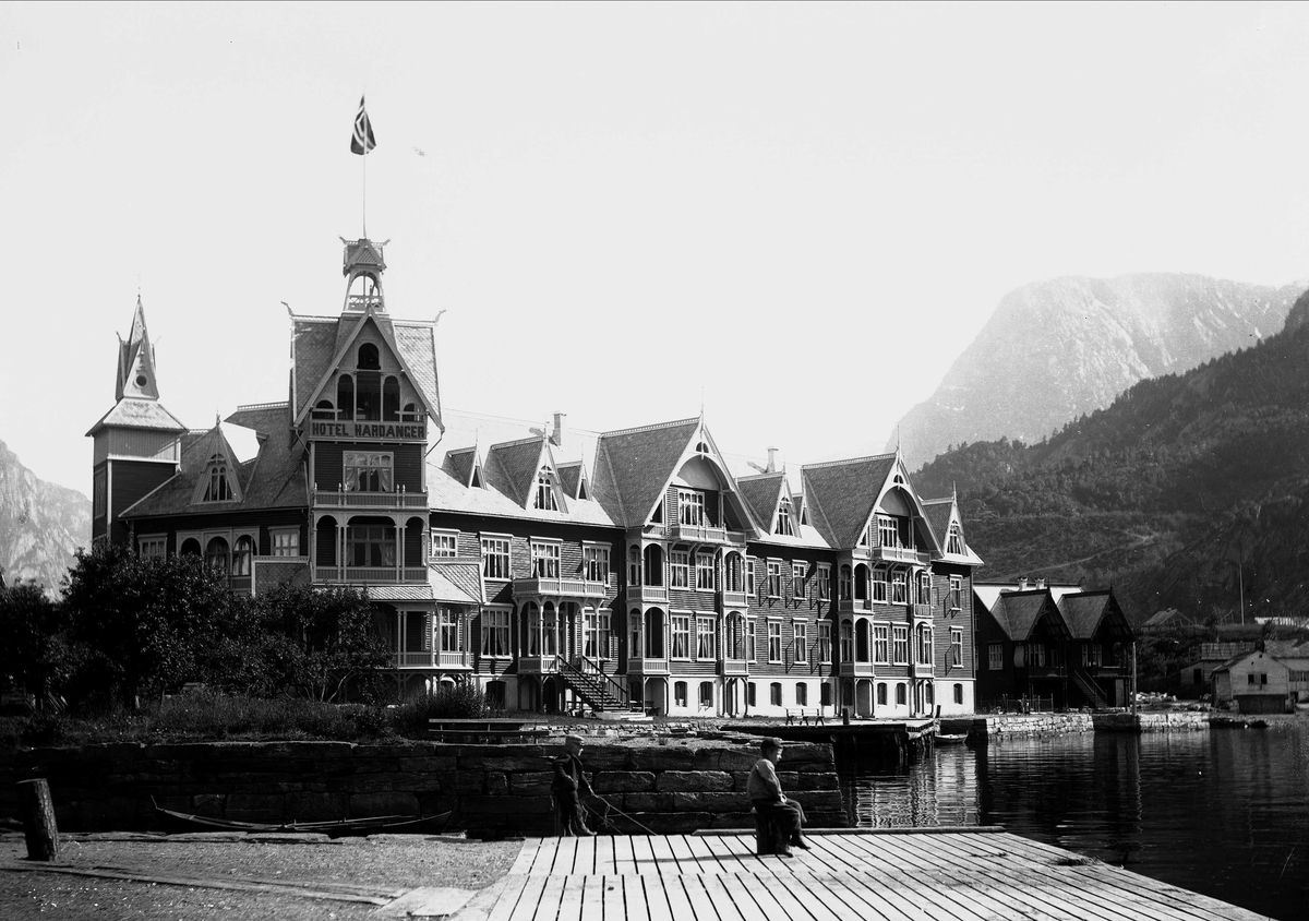 Odda i Hardanger.Hardanger Hotell. Fjellandskap i bakgrunnen. Foran på brygga ut mot Sørfjorden står to unggutter.