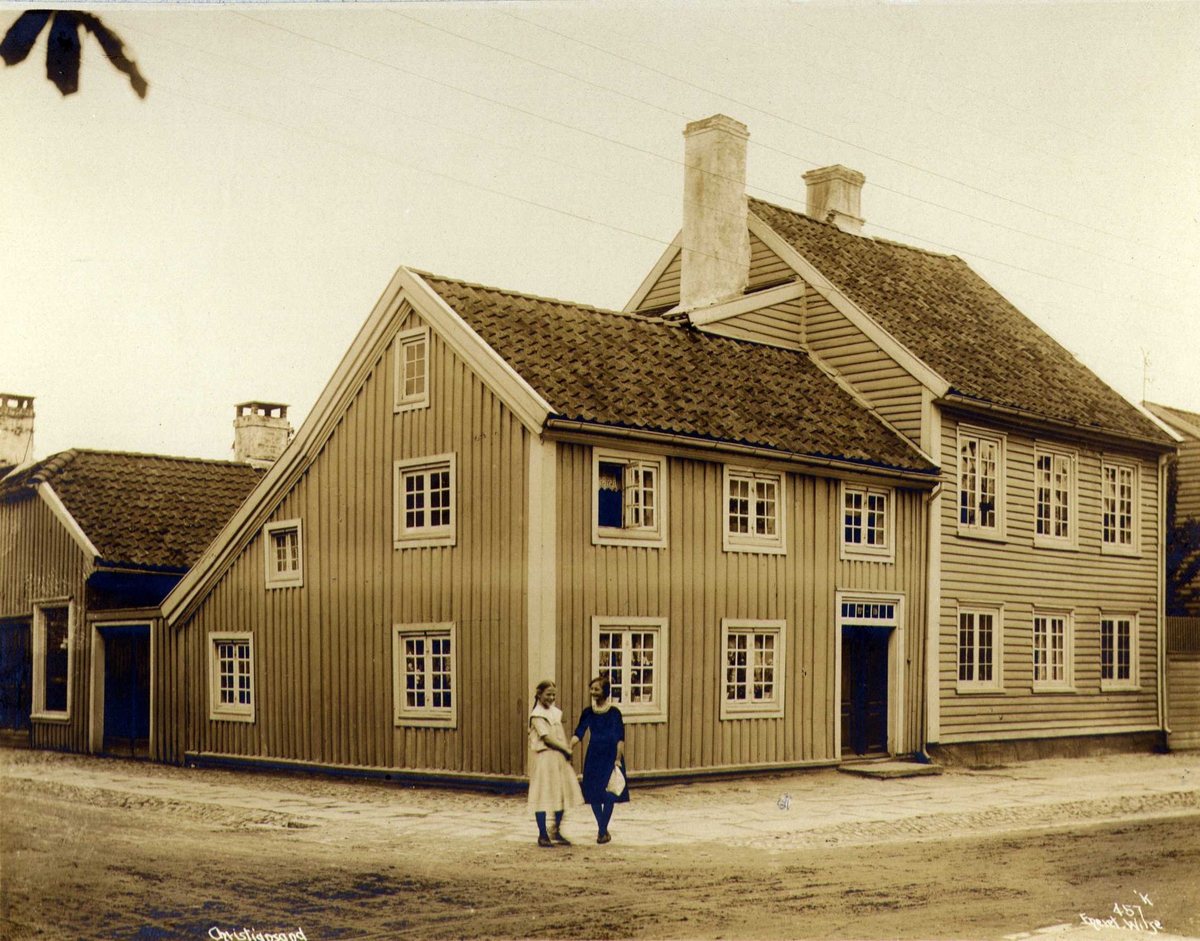 Gateløp med trebygninger, Kristiansand, Vest-Agder. To jenter i forgrunnen.