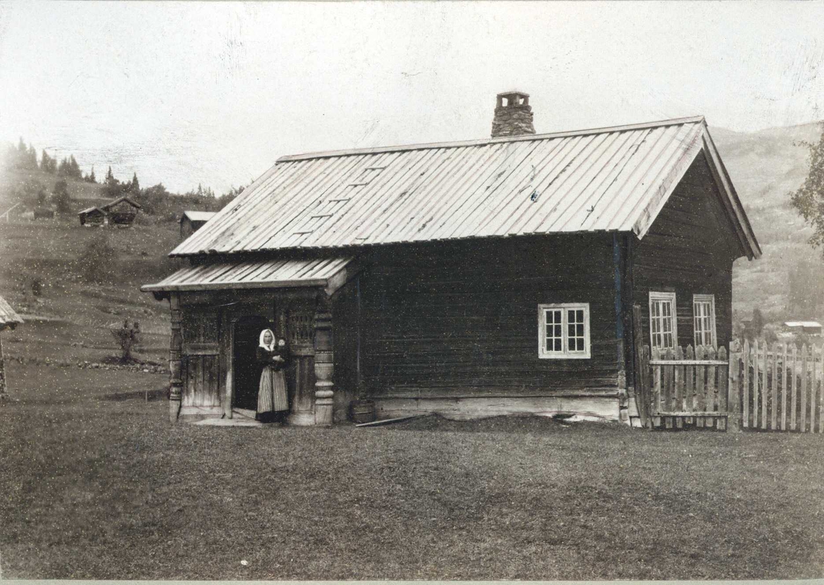 Stue, Nedre Åbø, Hjartdal, Telemark. Fotografert 1909. Kvinne stående foran stuen.