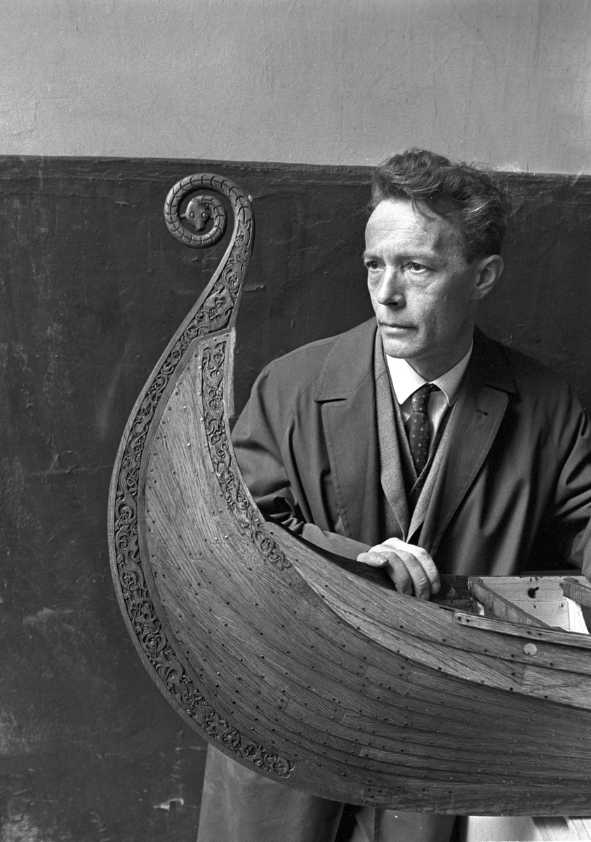 Serie. To menn bærer ut en modell av vikingeskipet "Osebergskipet" av en kjeller. Fotografert 1967.