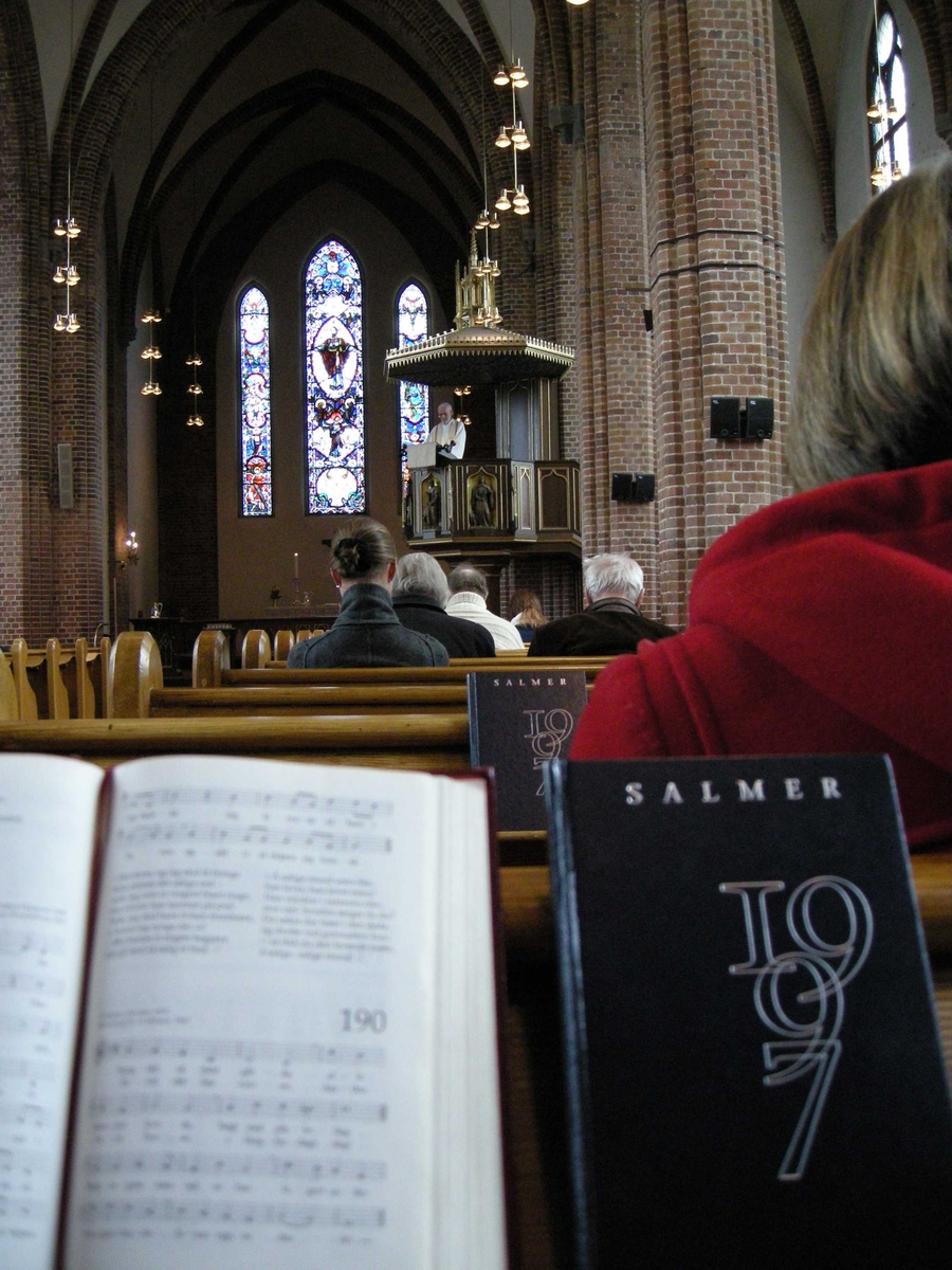 2. påskedag i Vestre Aker kirke, Oslo, 24.03.2008. Preken. Presten taler fra prekestolen i kirken. Menigheten sitter på kirkevenkene. Salmebøker.