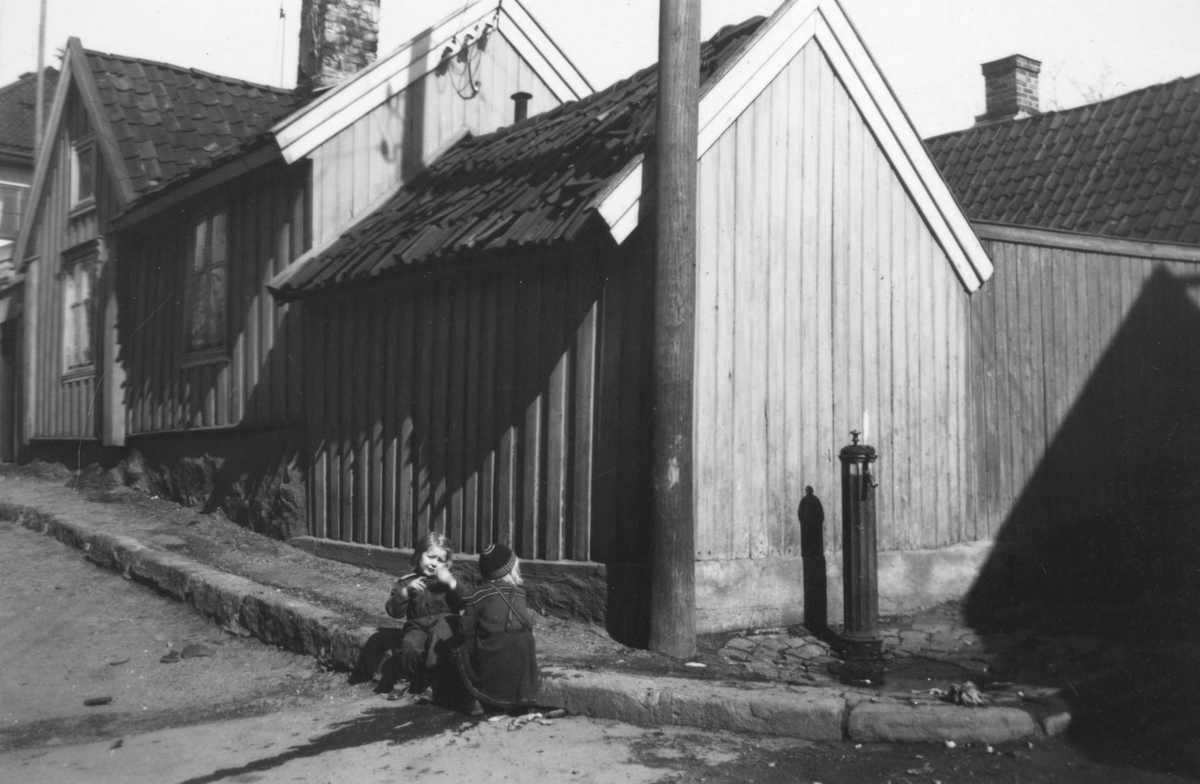 Fra trehusmiljøet på Enerhaugen, Oslo. Gateparti med vannpost og barn på fortauet ved Johannesgata 12-14.